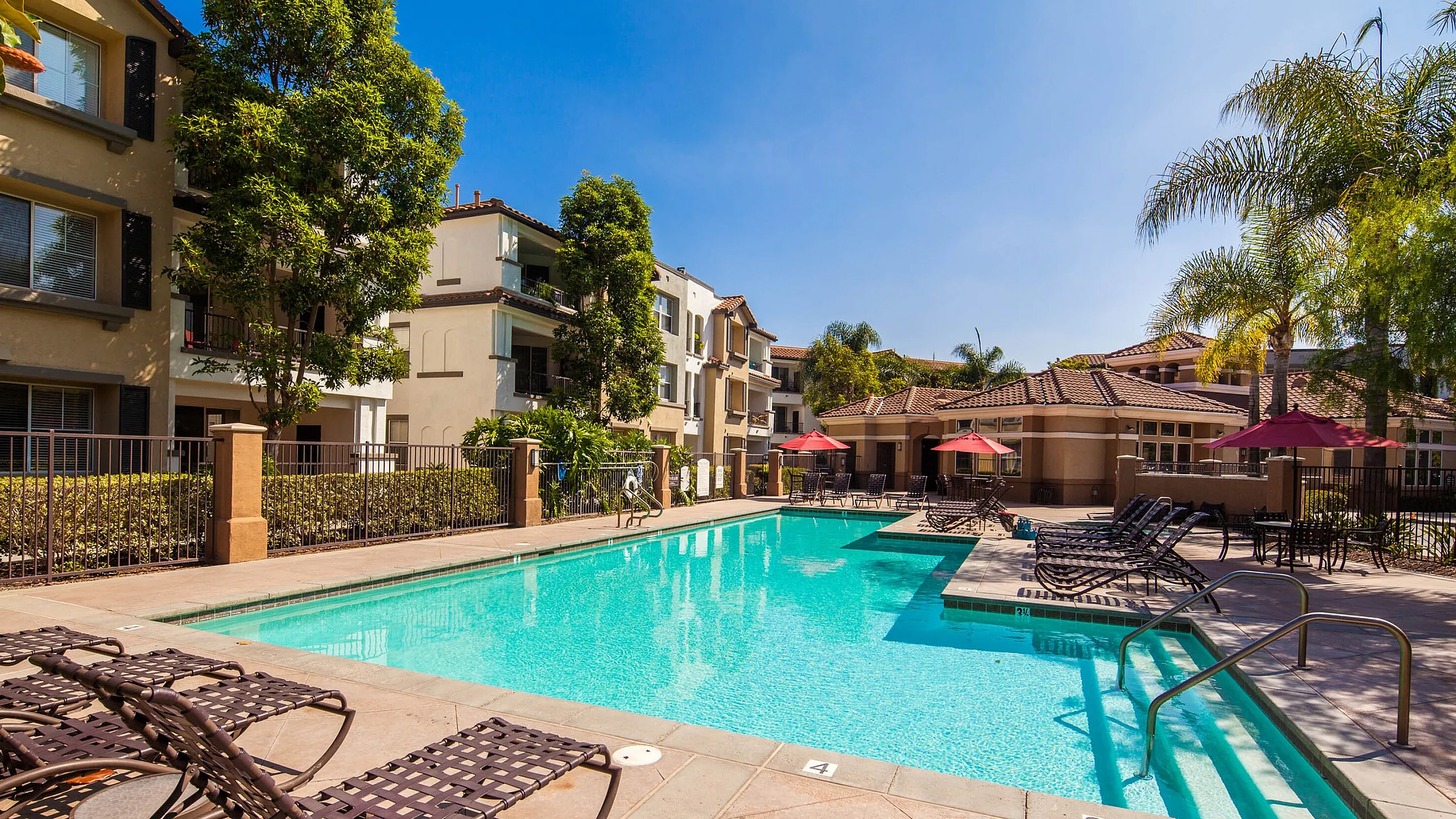 Large sparkling community pool surrounded by lounge chairs and umbrellas for resident relaxation.
