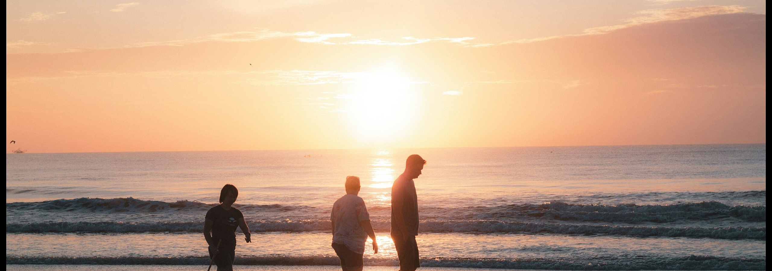 three people walking on the beach