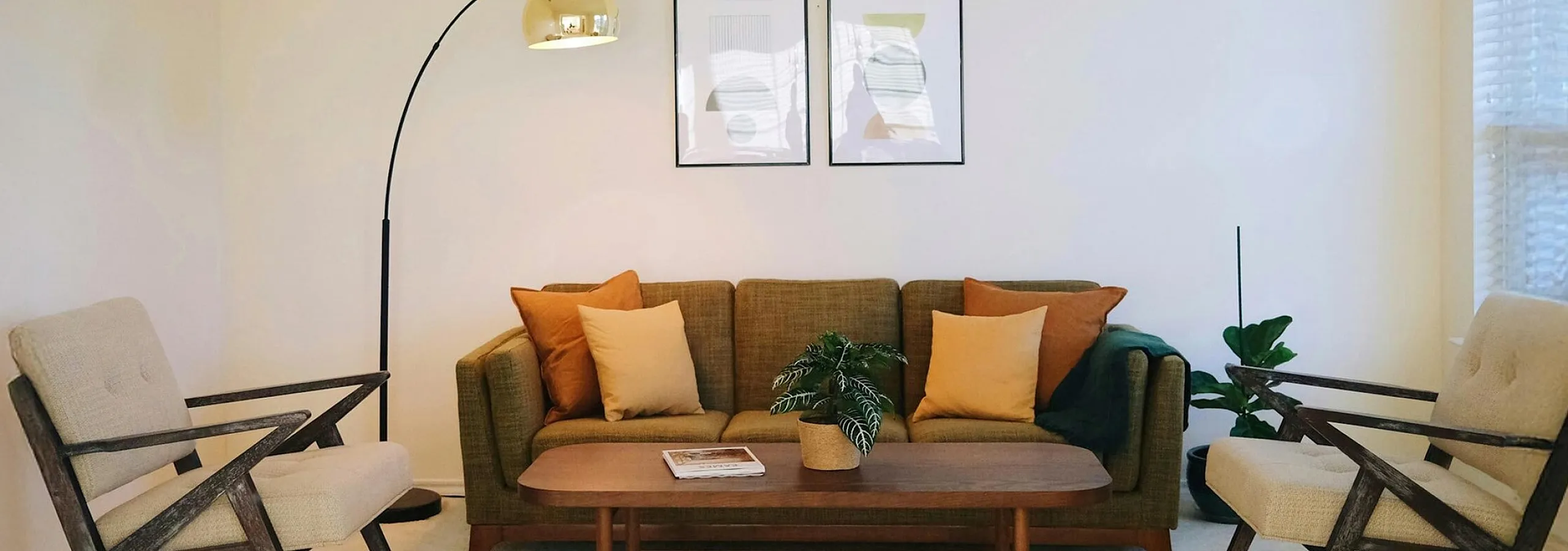 Taupe sofa with decorative pilows and wooden coffee table with chairs at the sides