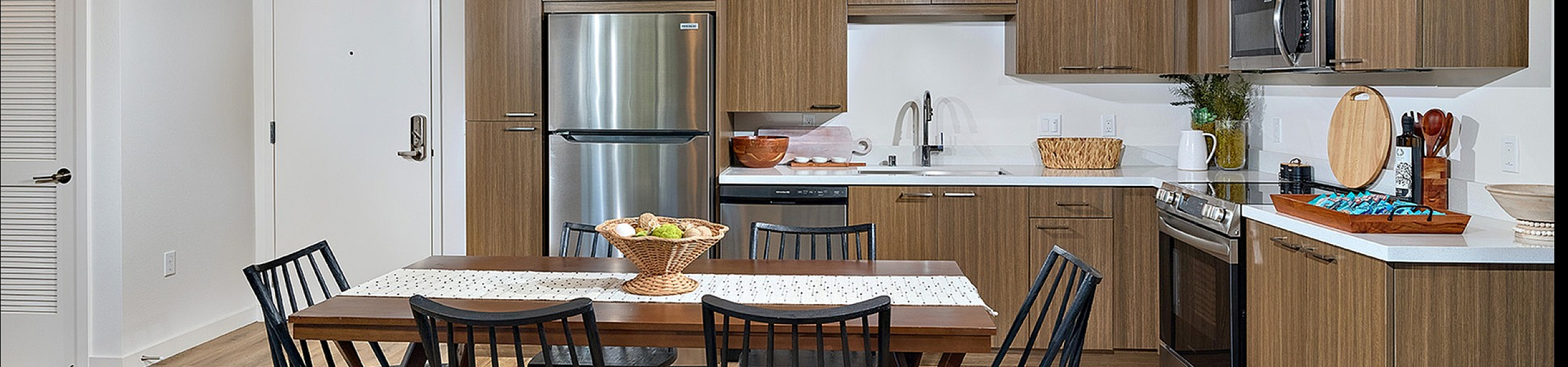 open kitchen layout with rectangle dining table and faux wood like flooring at Dezi