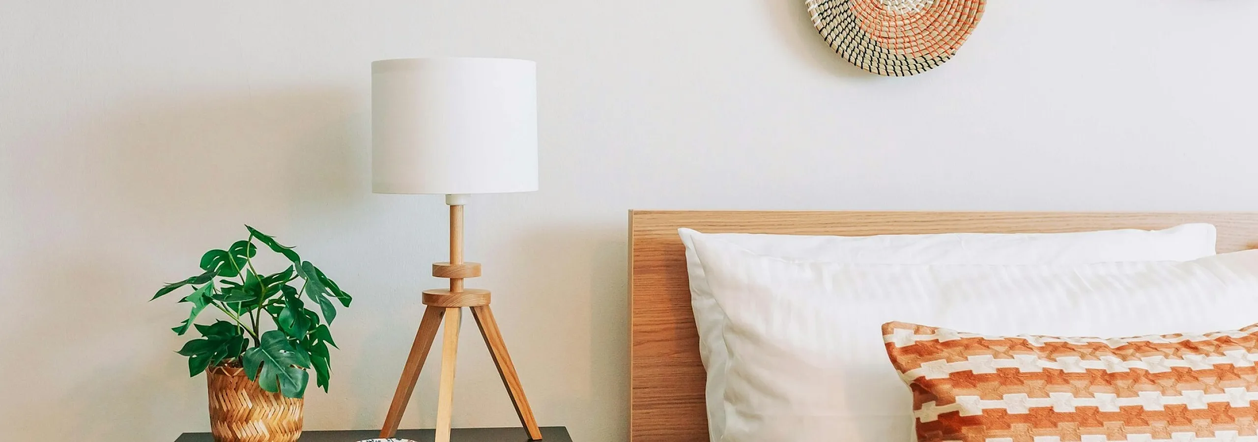 bed with wooden bed frame and accent pillows next to lamp and drawers
