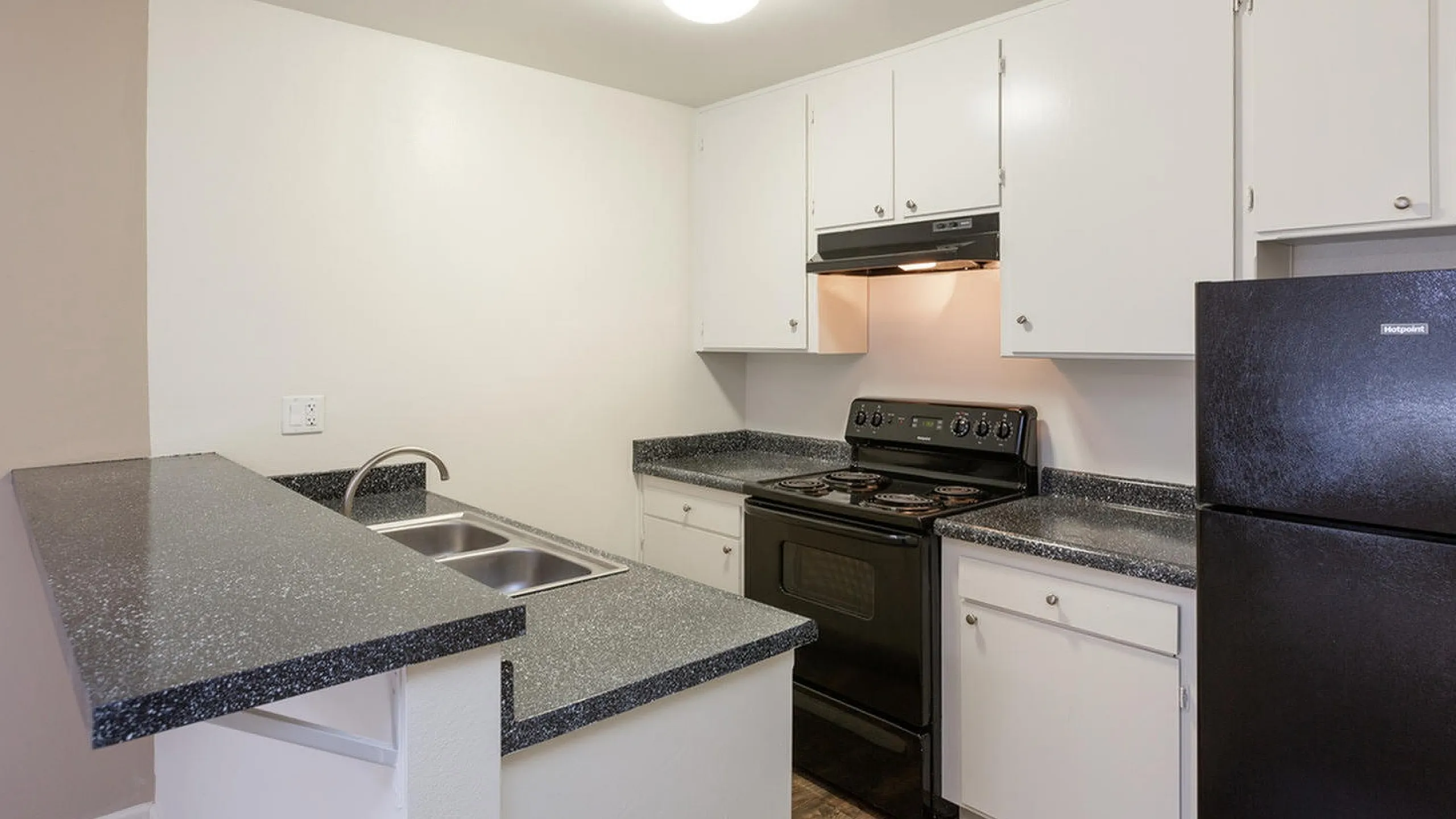Modern kitchen with black appliances and white cabinetry at Elan - Sandrock Place