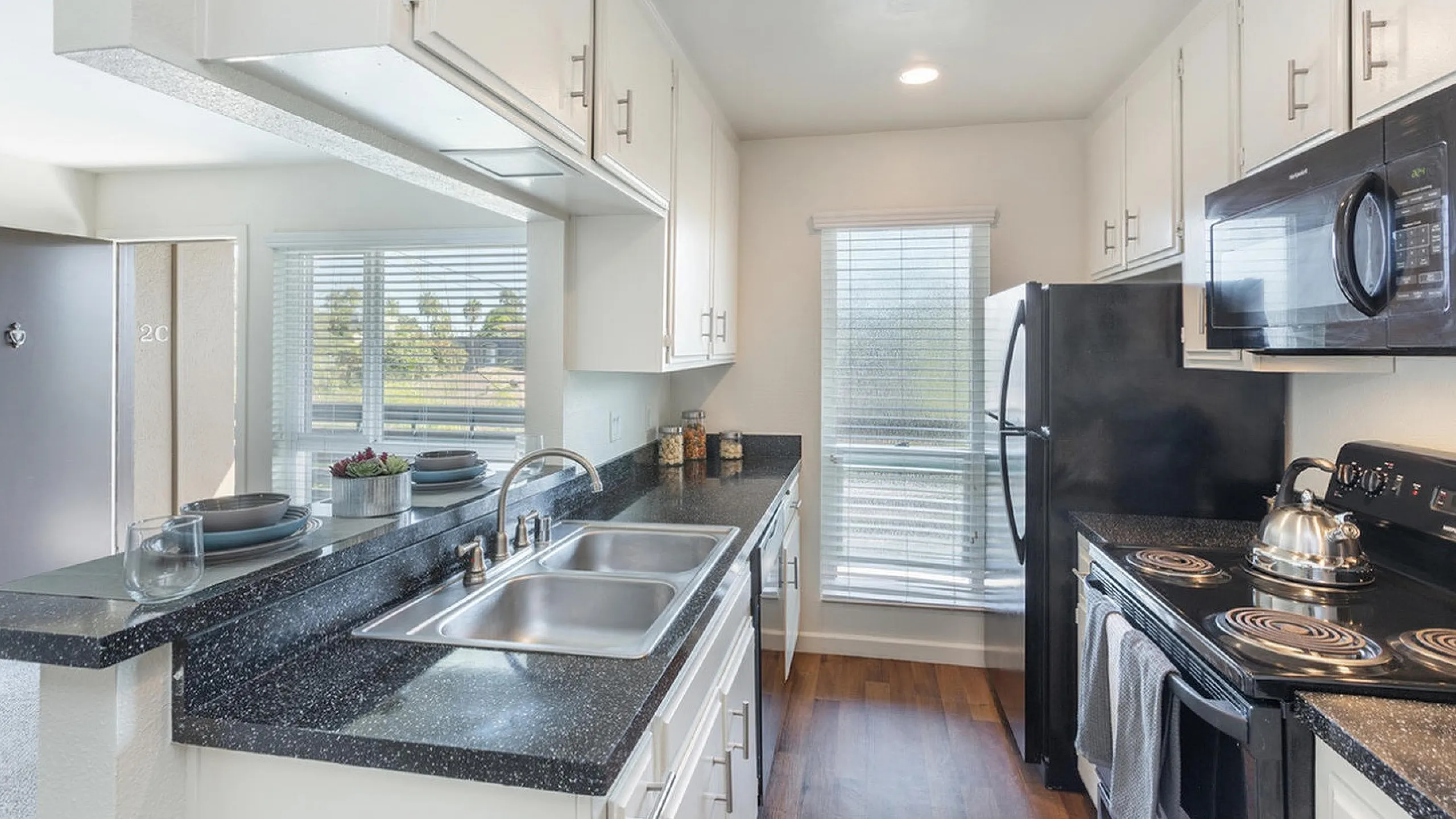 Modern kitchen with black appliances and granite-style counters at Elan - pacific lofts
