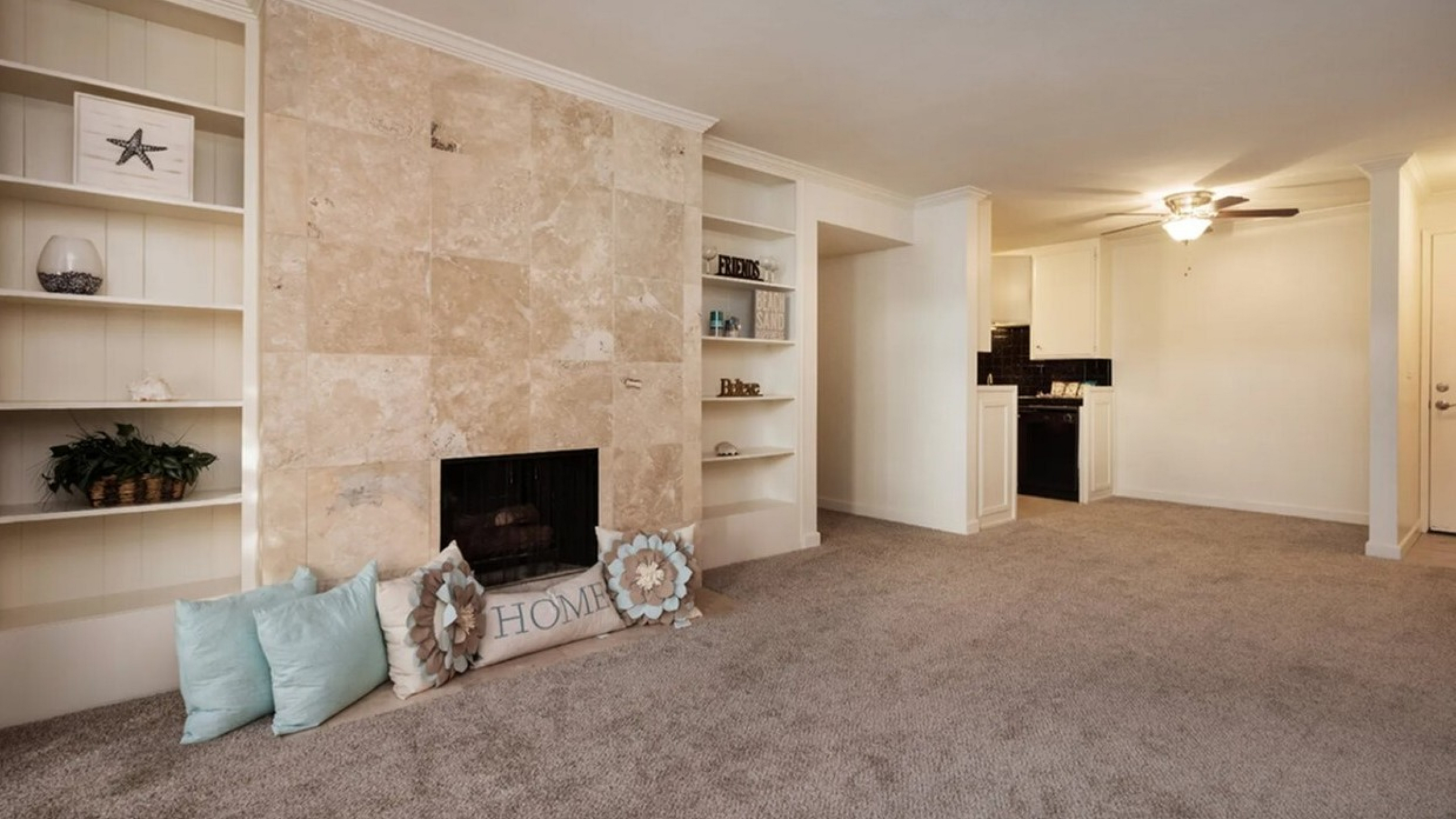 Living room with a cozy fireplace and built-in shelving at Elan - bella mer coronado.