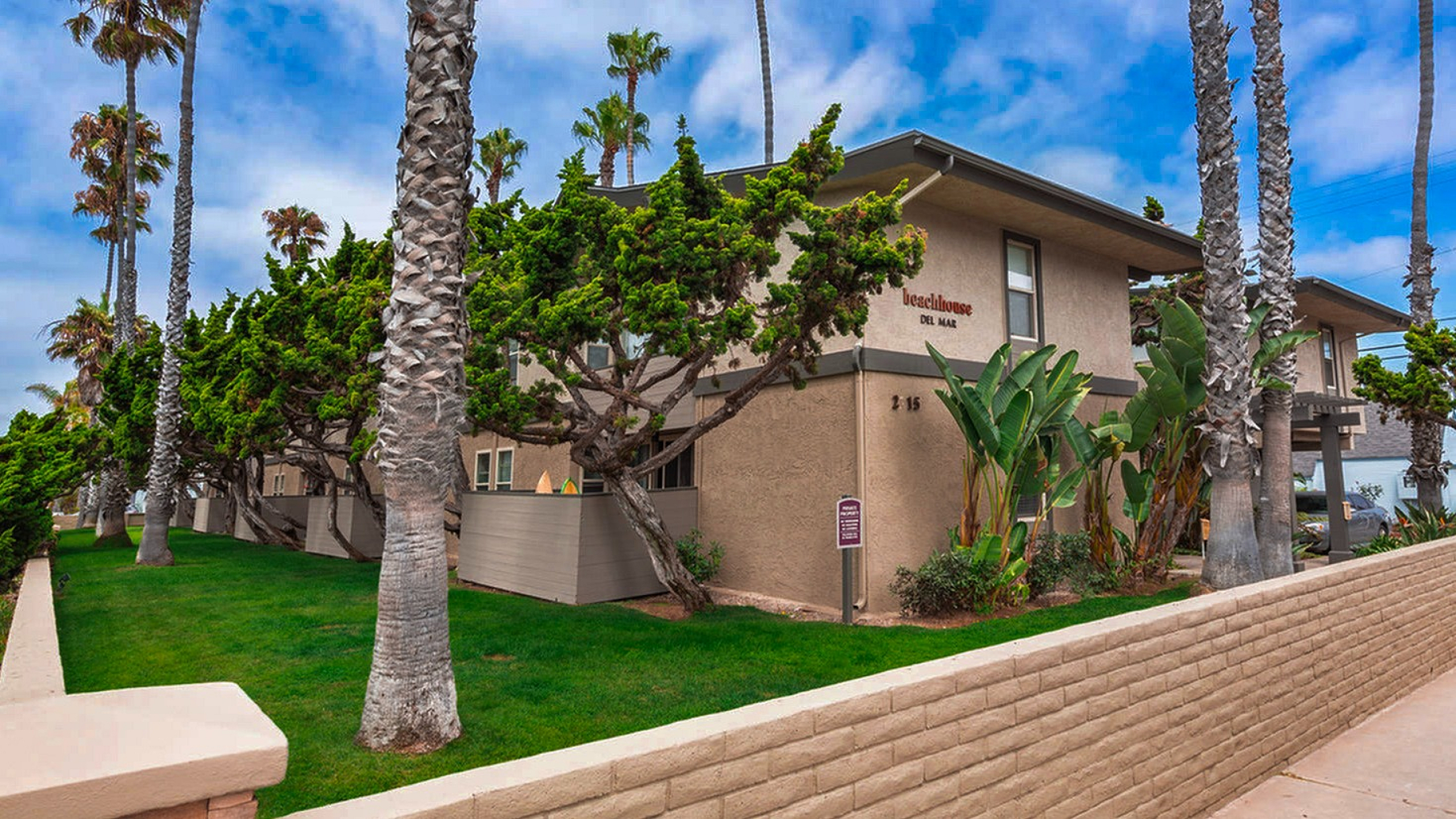 Coastal apartment building with palm trees and lawn at Elan - beachhouse del mar