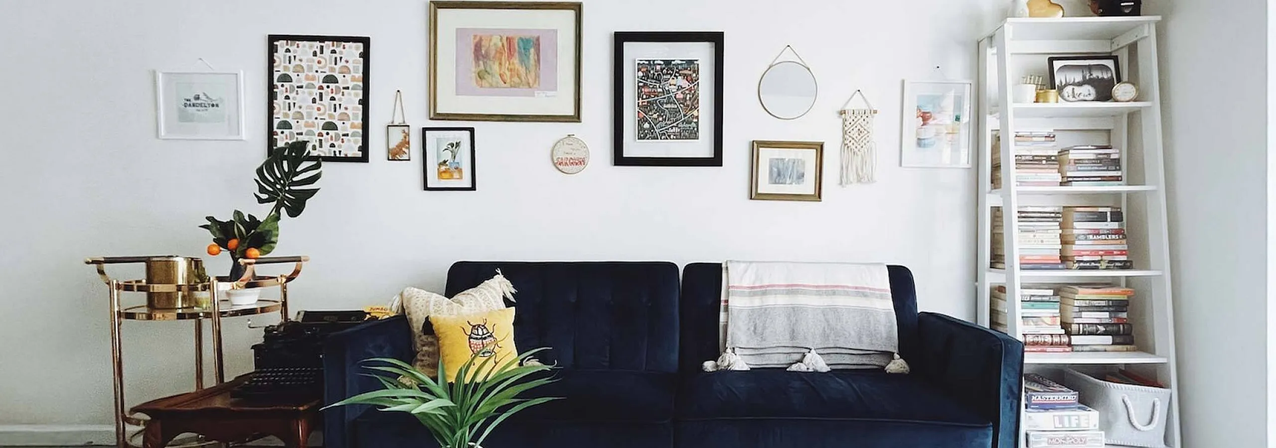 blue suede sofa with decorative pillows and artwork behind