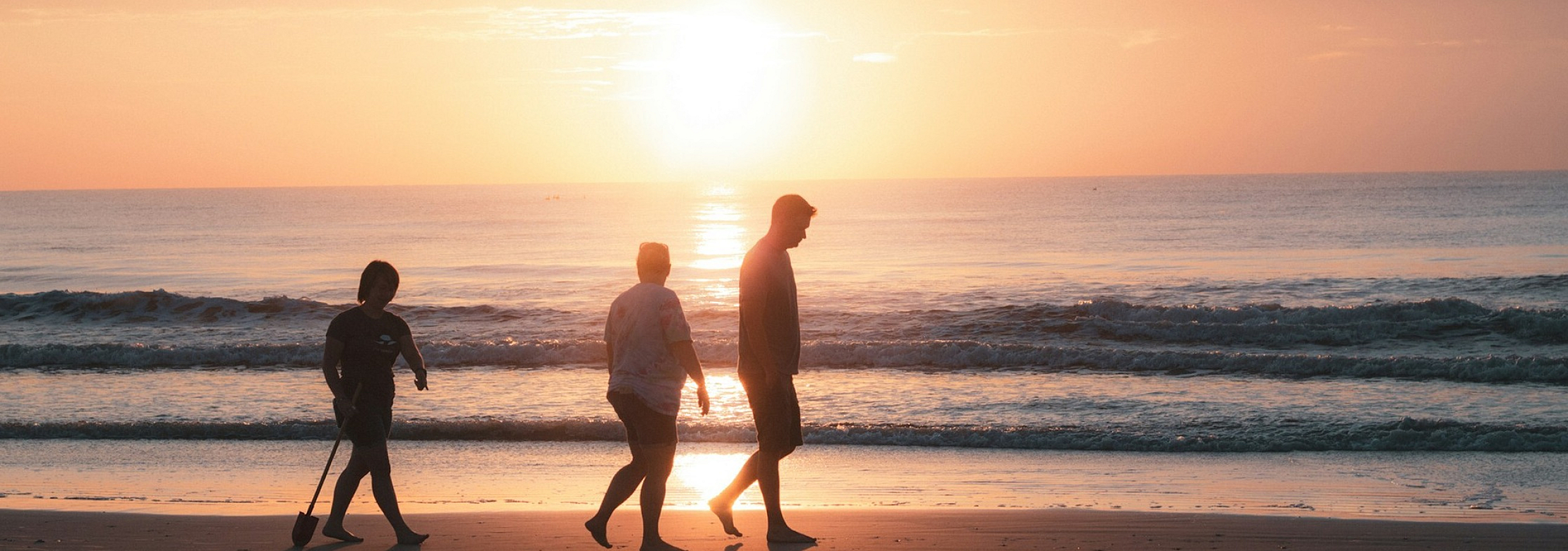 three people walking on the beach