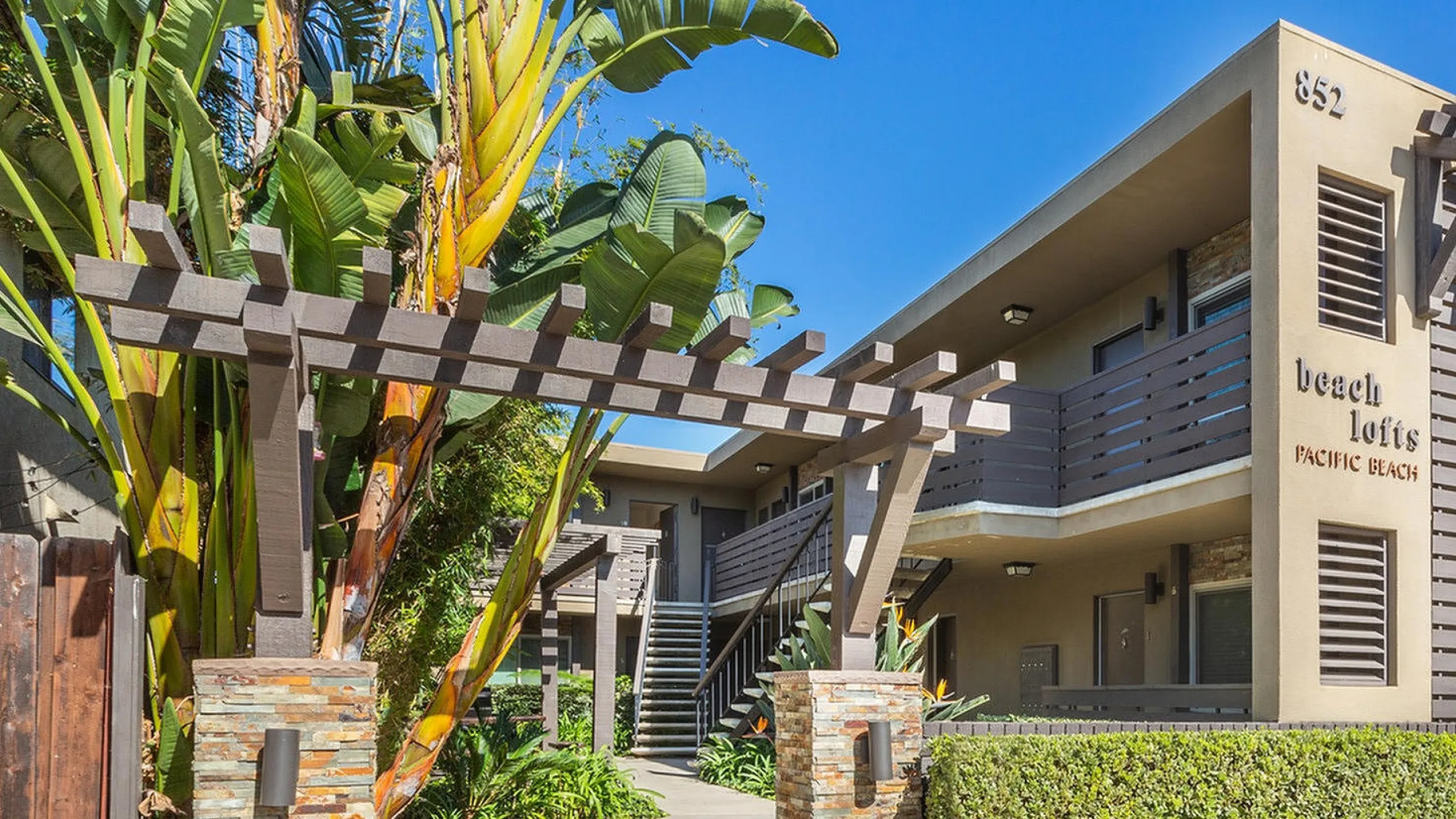 Shaded courtyard walkway with a wooden trellis and bench at Elan - beachlofts del mar