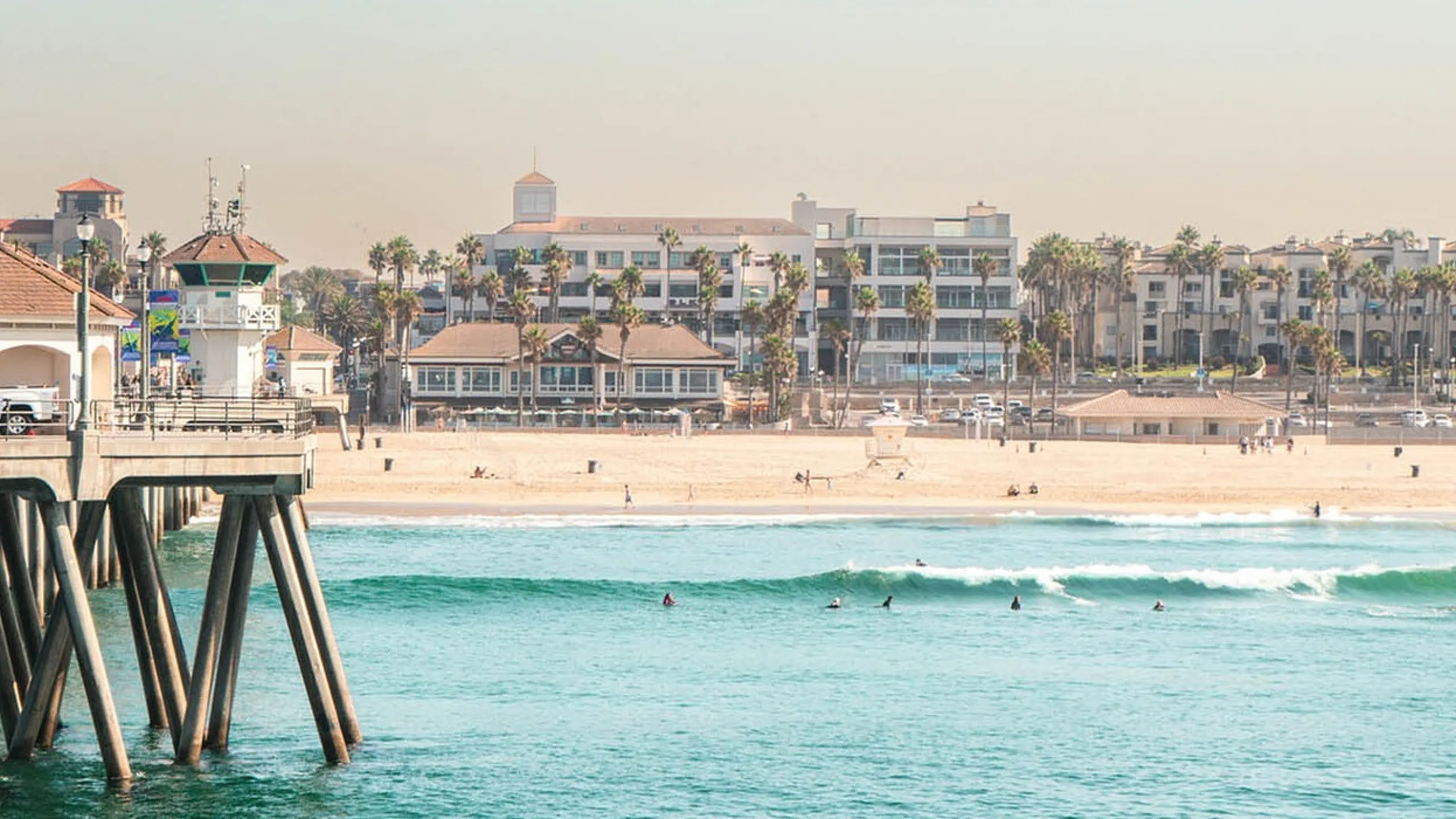 people surfing at the beach and the pier to the left
