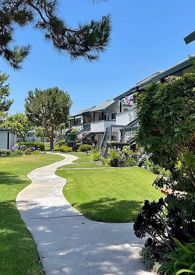 Manicured lawn, shade trees, and concrete path outside Delaware Pines apartment residences.