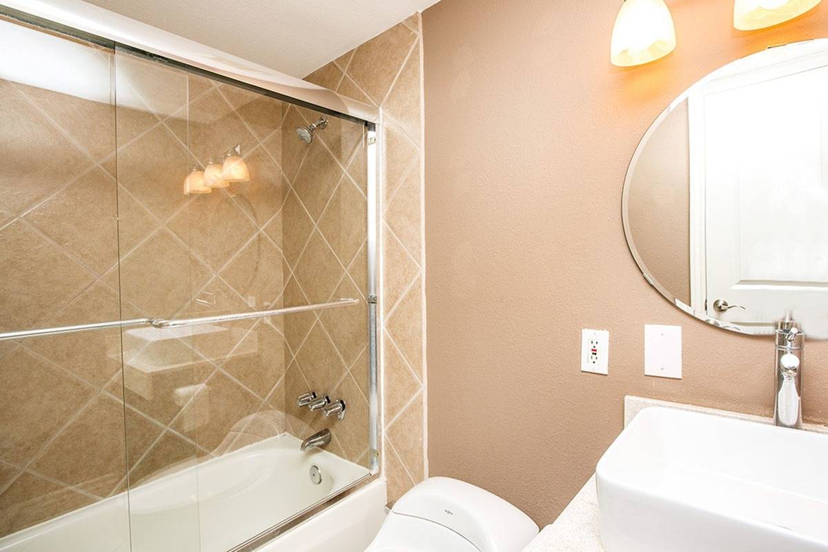 full bath with shower doors and tiled shower tub combo and white vanity at Solaris at The Biltmore