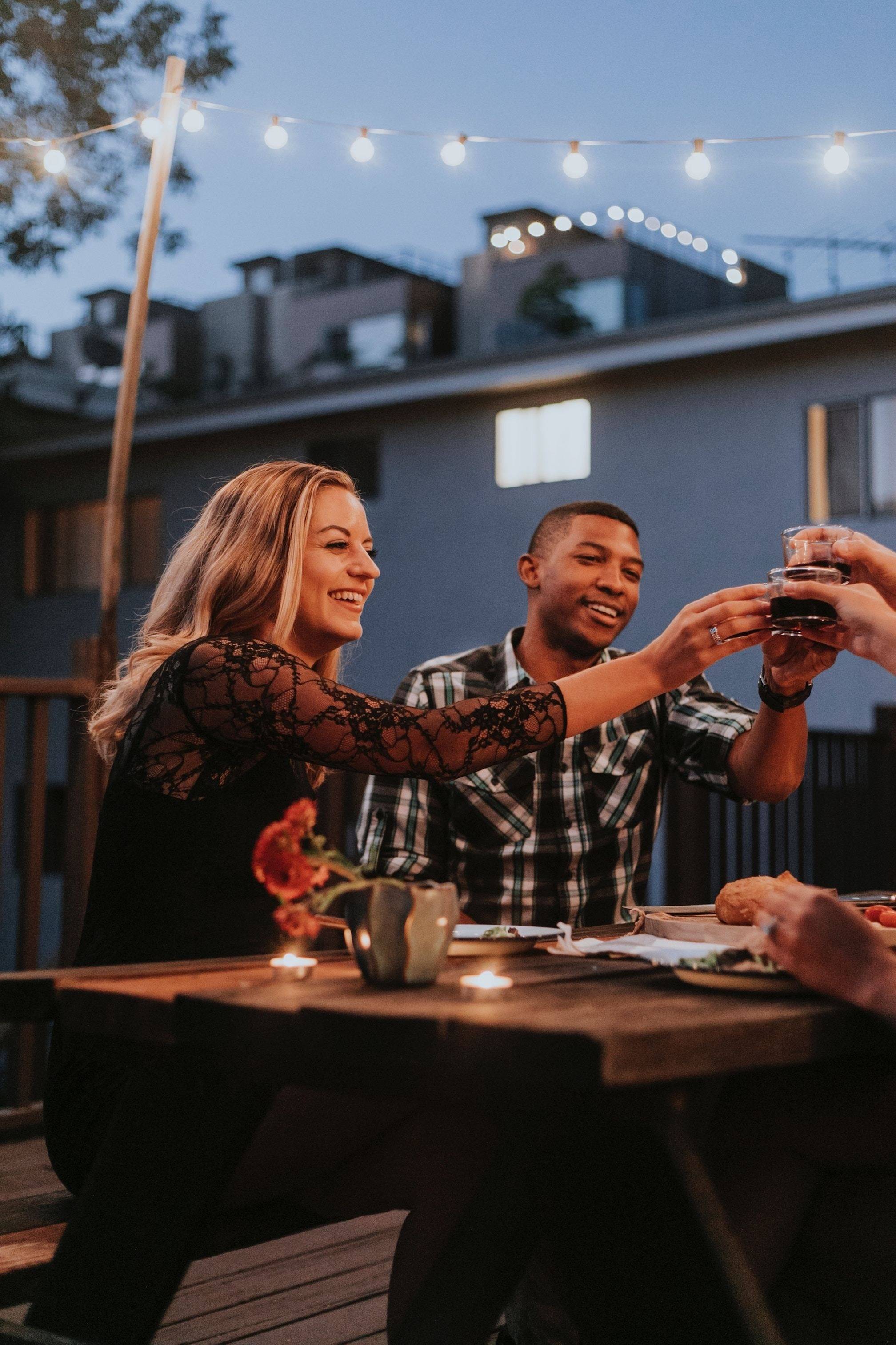 man and woman dining in patio and toasting with drinks
