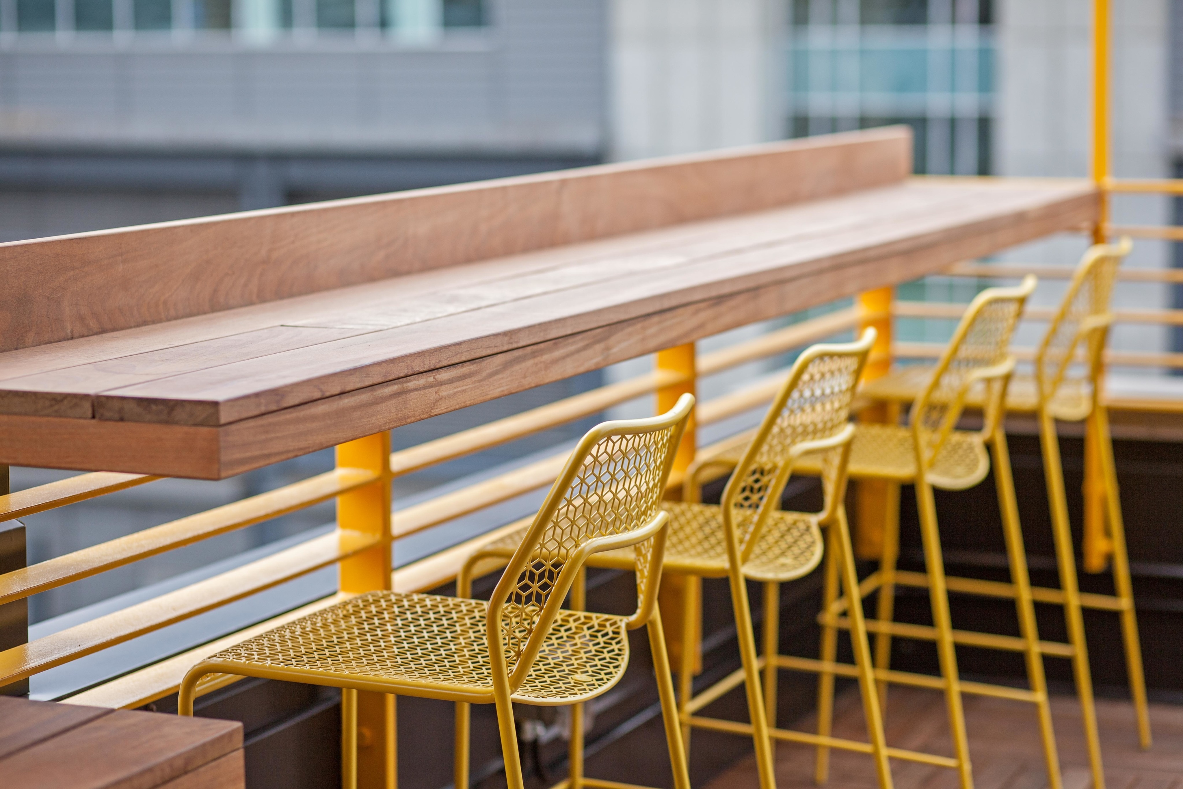 bar with yellow bar chairs at oro apartments rooftop