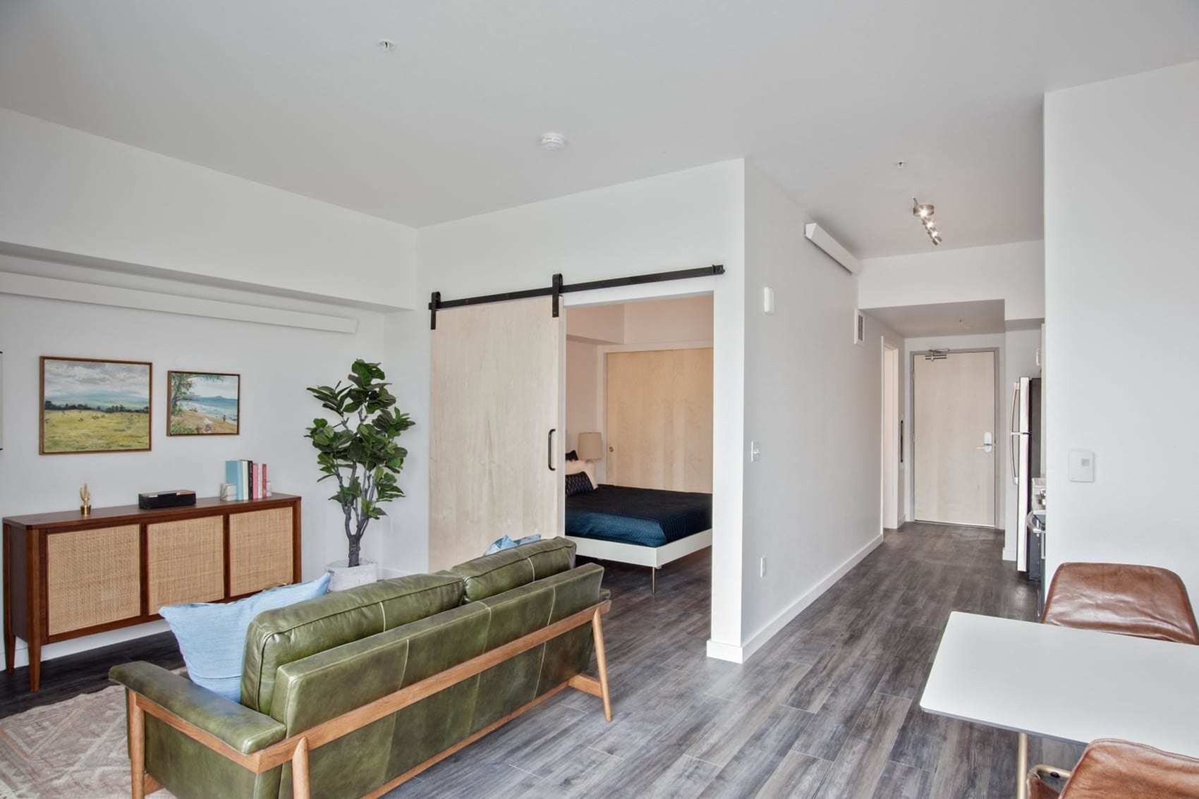 One BR Apartments in Downtown Portland OR - ORO - An interior shot of The Open-Concept Living Room Area with Large Sofa, Potted Plant, and Area Rug