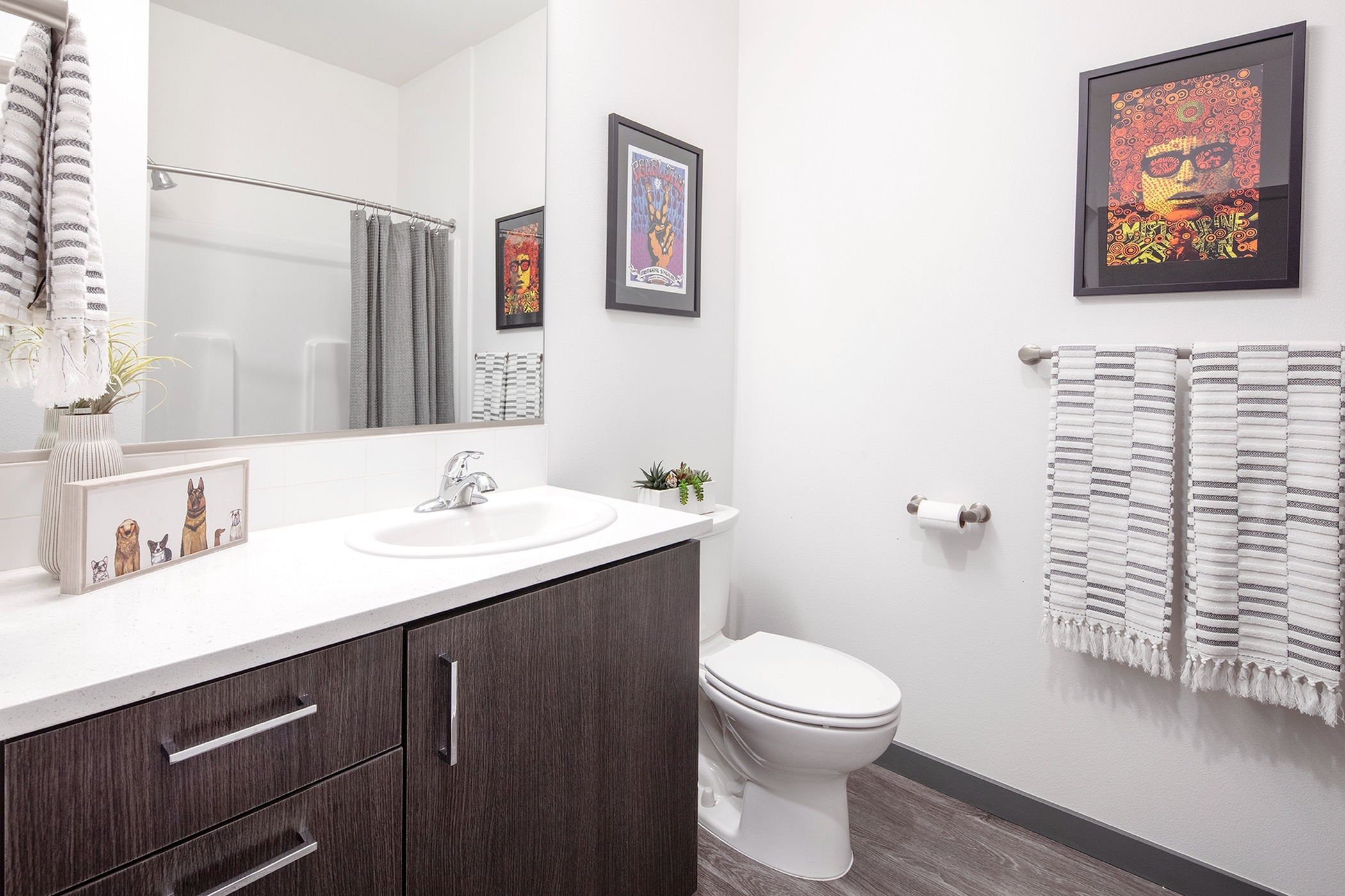 Apartments For Rent Williams District - Bathroom That Has Full Bath With Shower, Vinyl Wood Flooring, Large Mirror, And White Quartz Countertop.