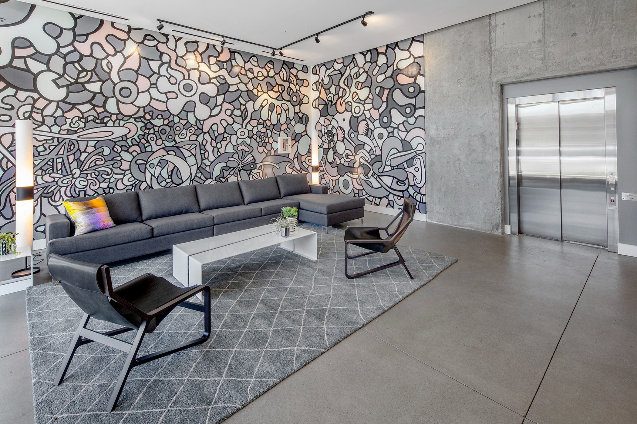 lobby with grey sofa and arm chairs and elevator at parallax apartments