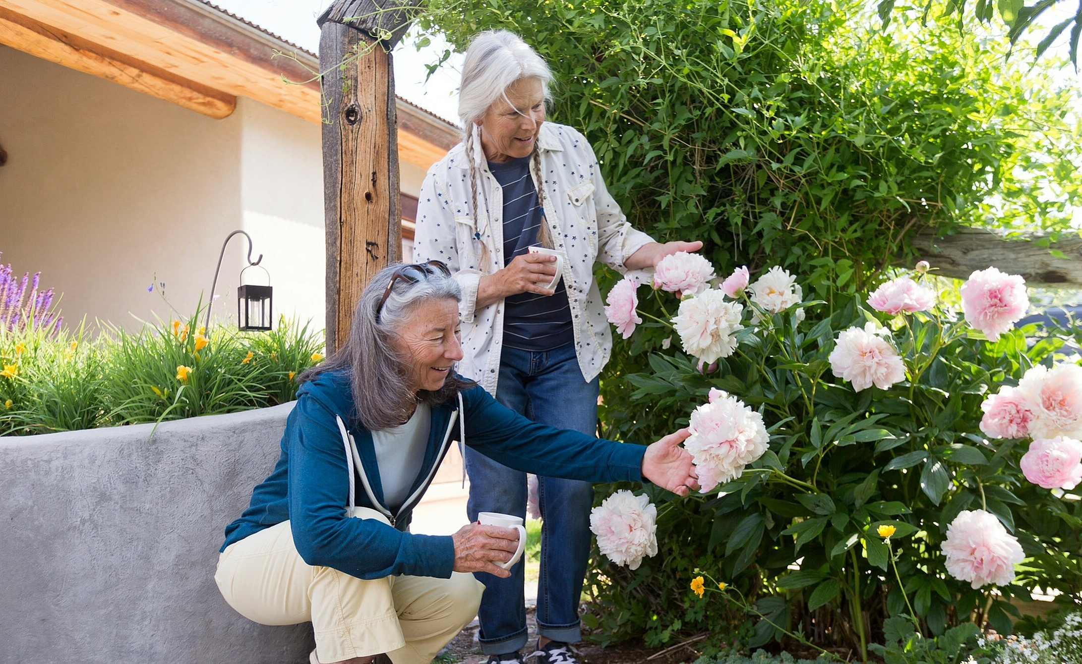 two women looking at flowers with cups of coffee