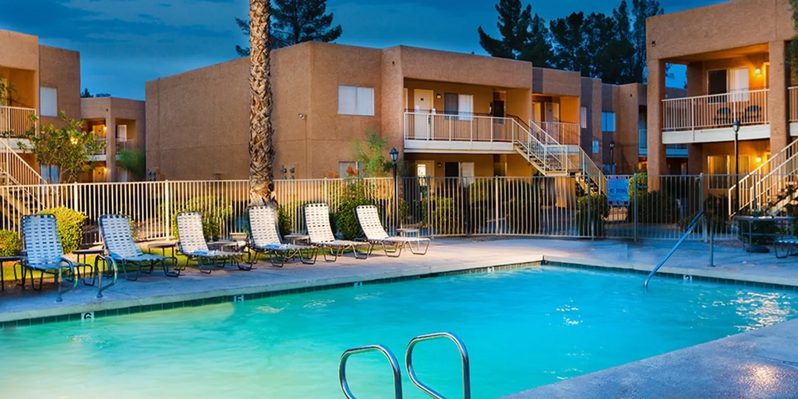 lit pool with lounge chairs at Metro on Main at night