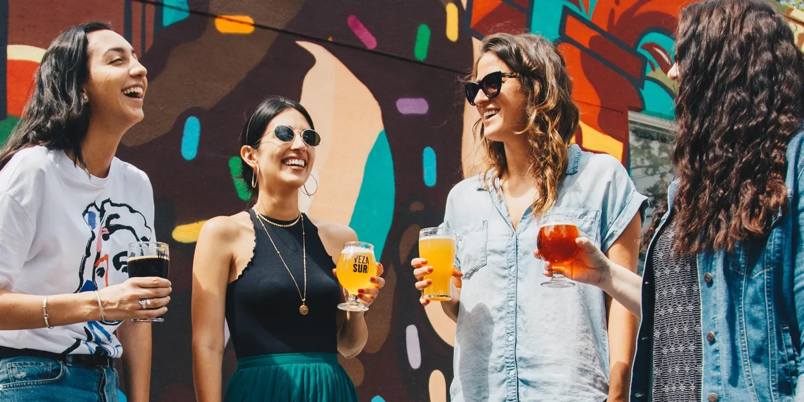 friends drinking beers infront of mural