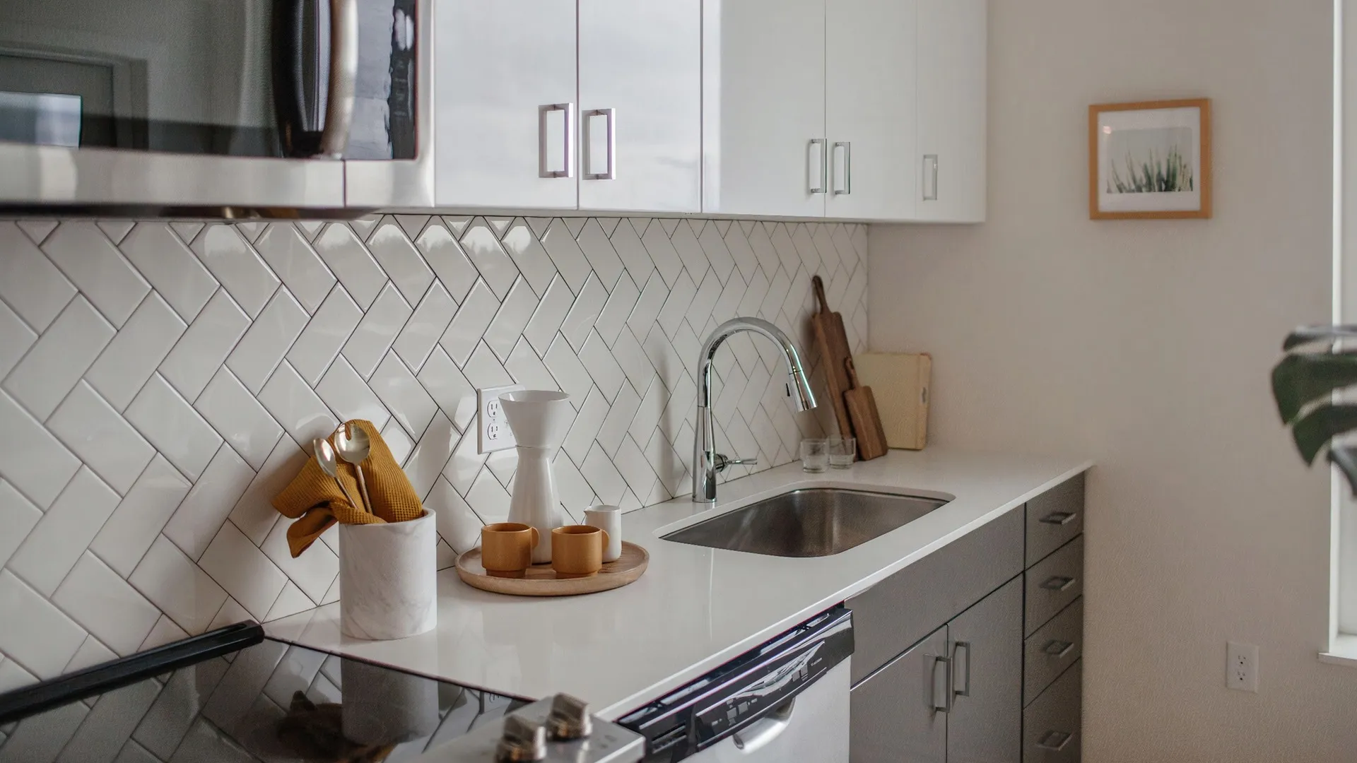 Kitchen with stainless-steel appliances, subway tile backsplash, luxury plank flooring, quartz countertops, and dual-tone cabinets