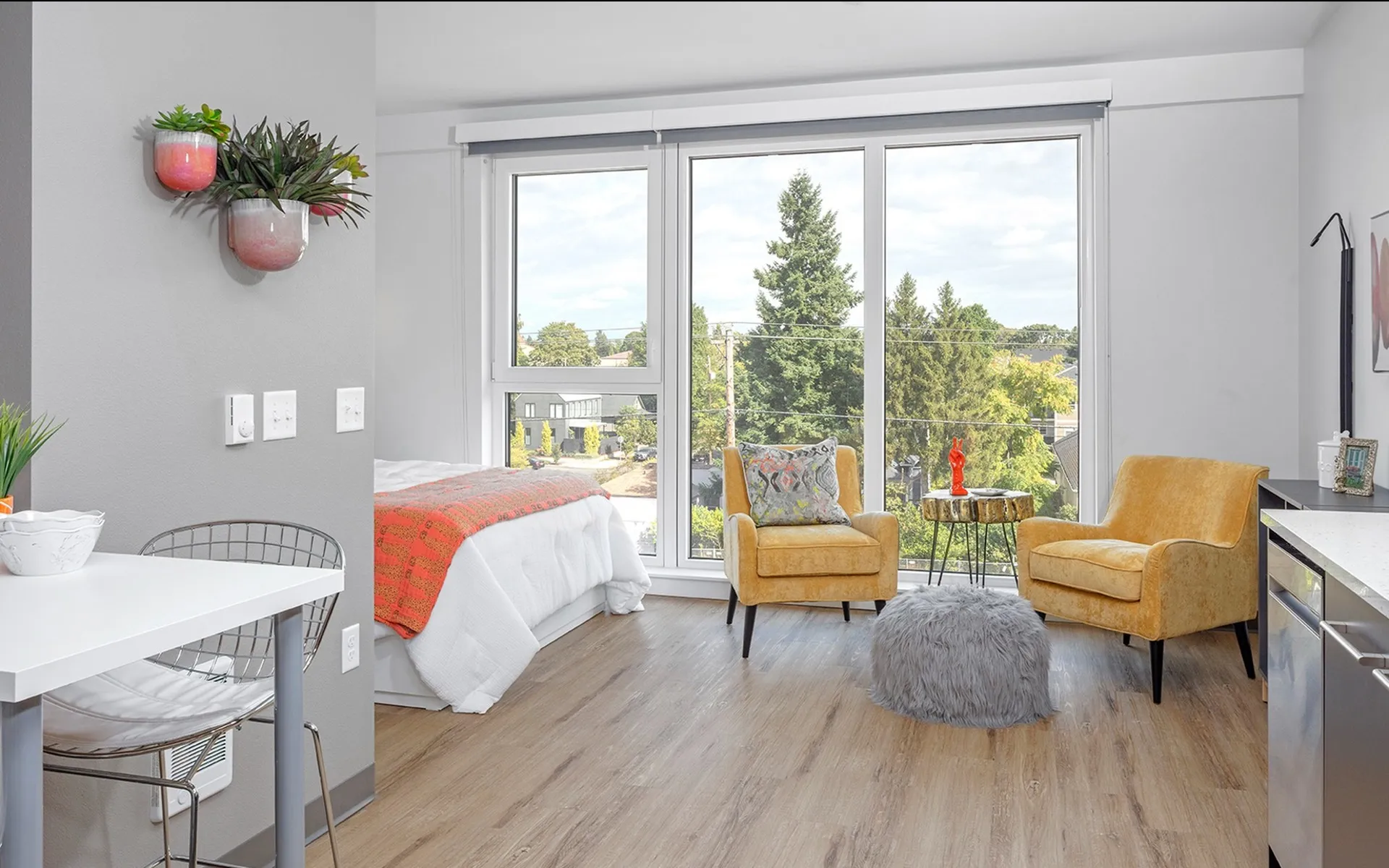 studio apartment with floor to ceiling windows and 2 armchairs at aniva apartments