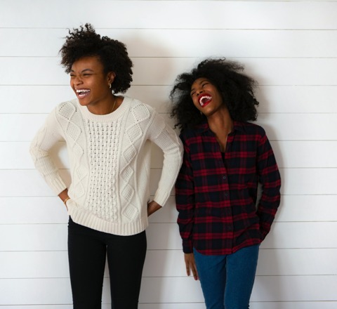 two women in front of a wall laughing