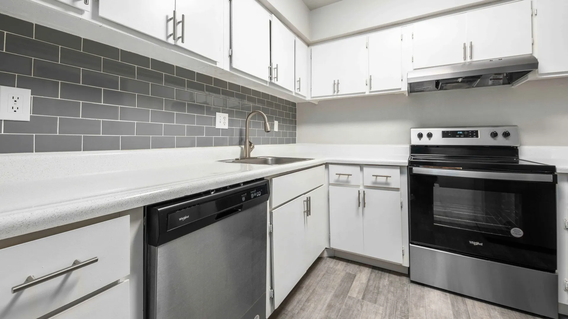 kitchen with stainless steel appliances, ceramic subway tile backsplash and faux hardwood flooring at peoria grand apartments