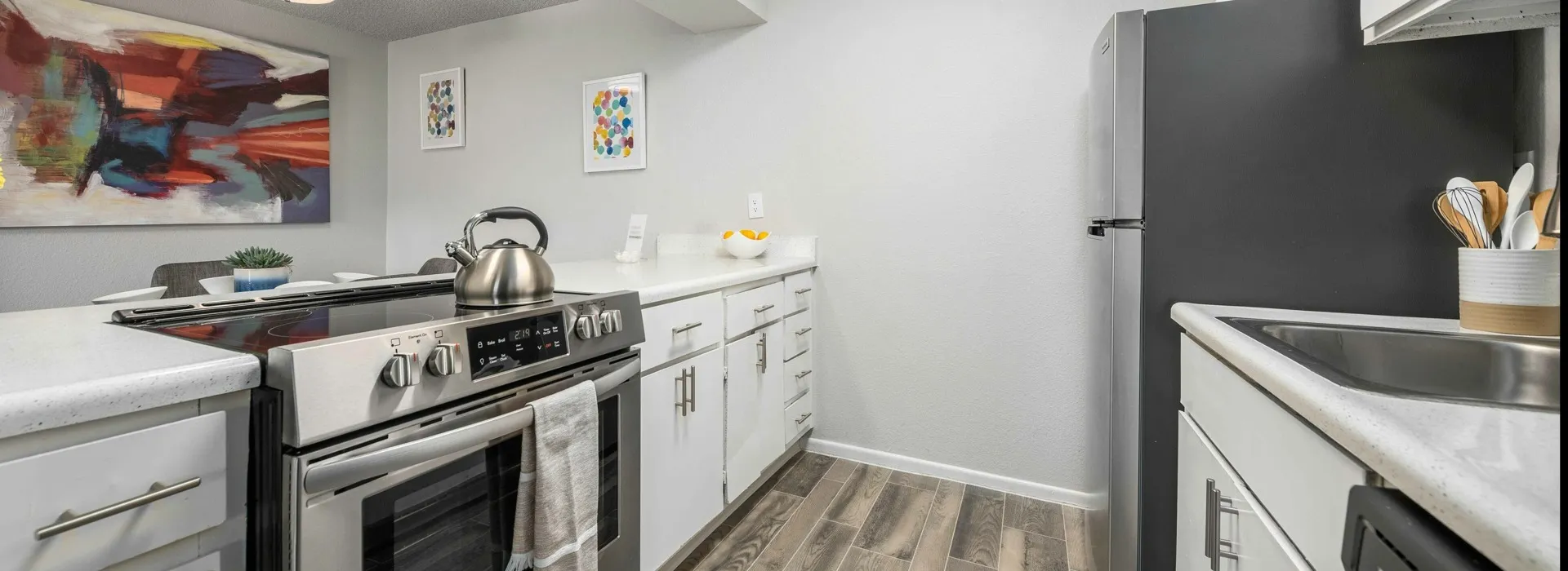 Kitchen with stainless steel appliances, wood inspired plank flooring, and updated white cabinetry