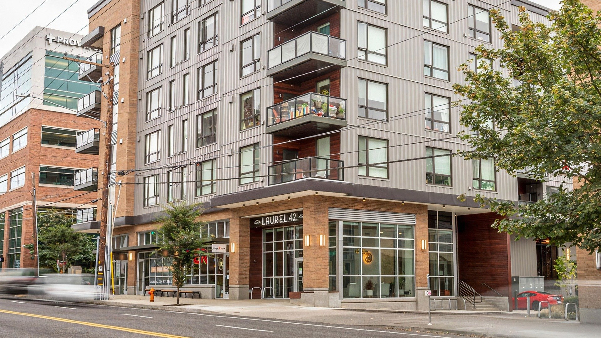 Exterior street view of community building, each floor has balconies and large windows. The ground floor shows the lobby entrance with a sign reading Laurel 42 above the doors.