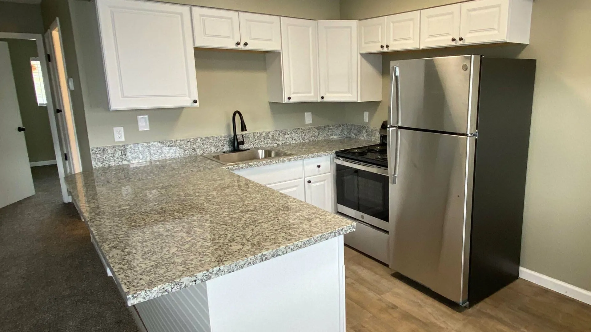 kitchen with black appliances bar area and wood inspired flooring at the creek at south carson