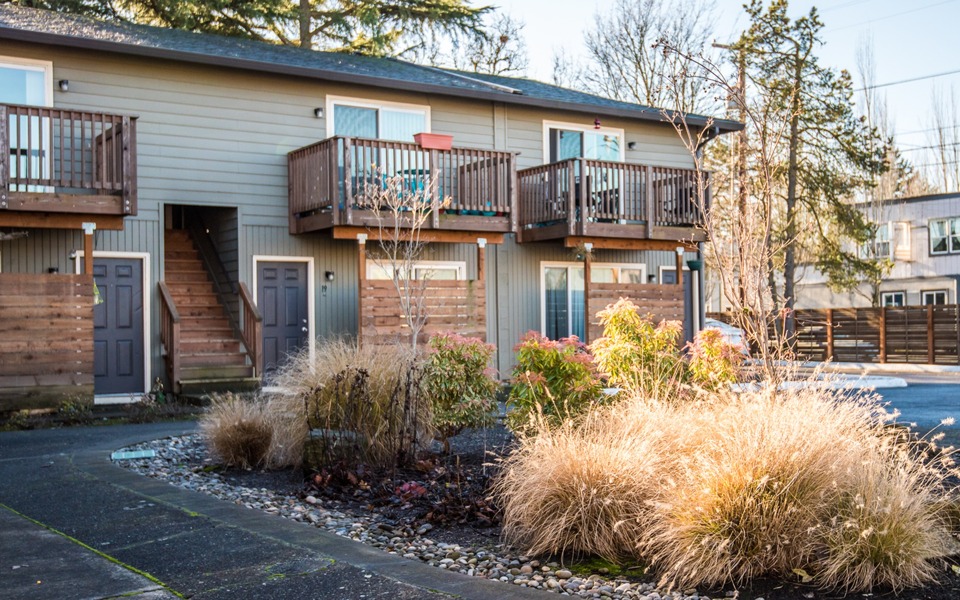 exterior building and parking lot showing balcony and patio of a two story building with foliage and a parking lot