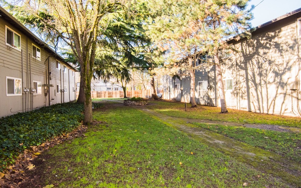 exterior community with 5 trees surrounding a rock wall flower bed lots of greenery