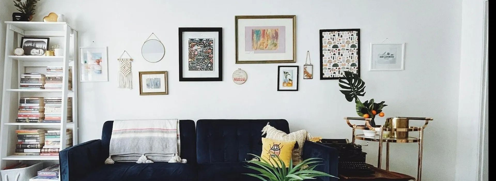 blue suade sofa with many pieces of art hanging behind