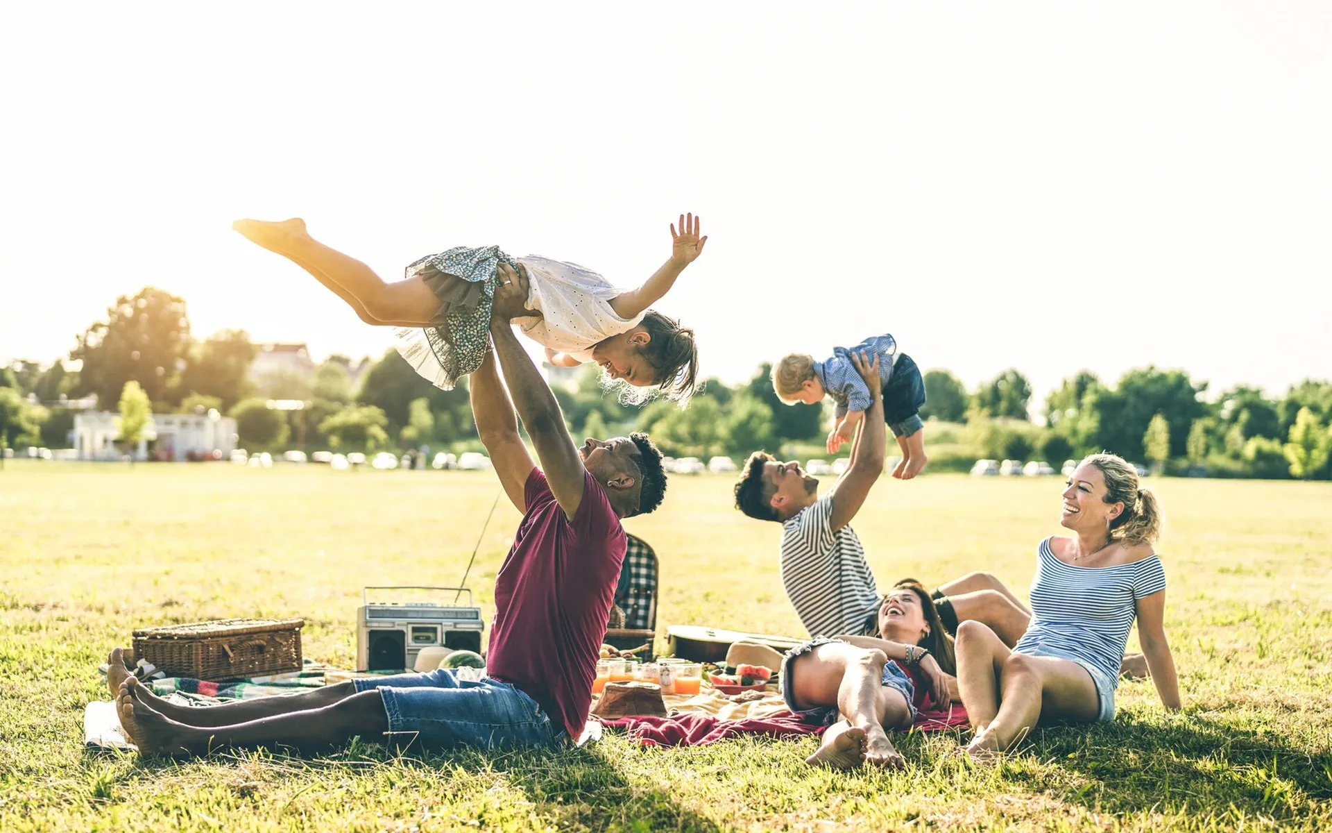 four people with two kids lying on the grass at the park