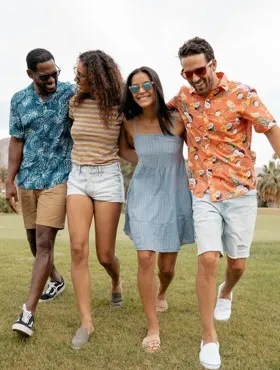 four people walking shoulder to shoulder across a grass field