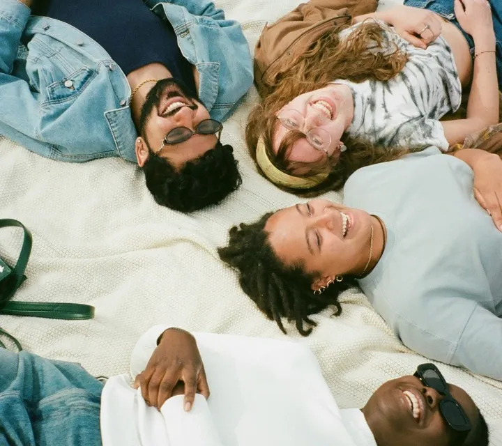 4 people laying on the ground on top of a blanket