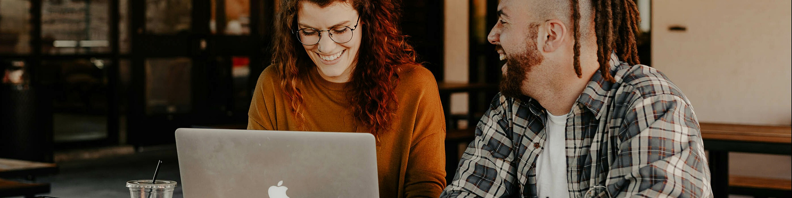 two people working on a laptop at a cafe