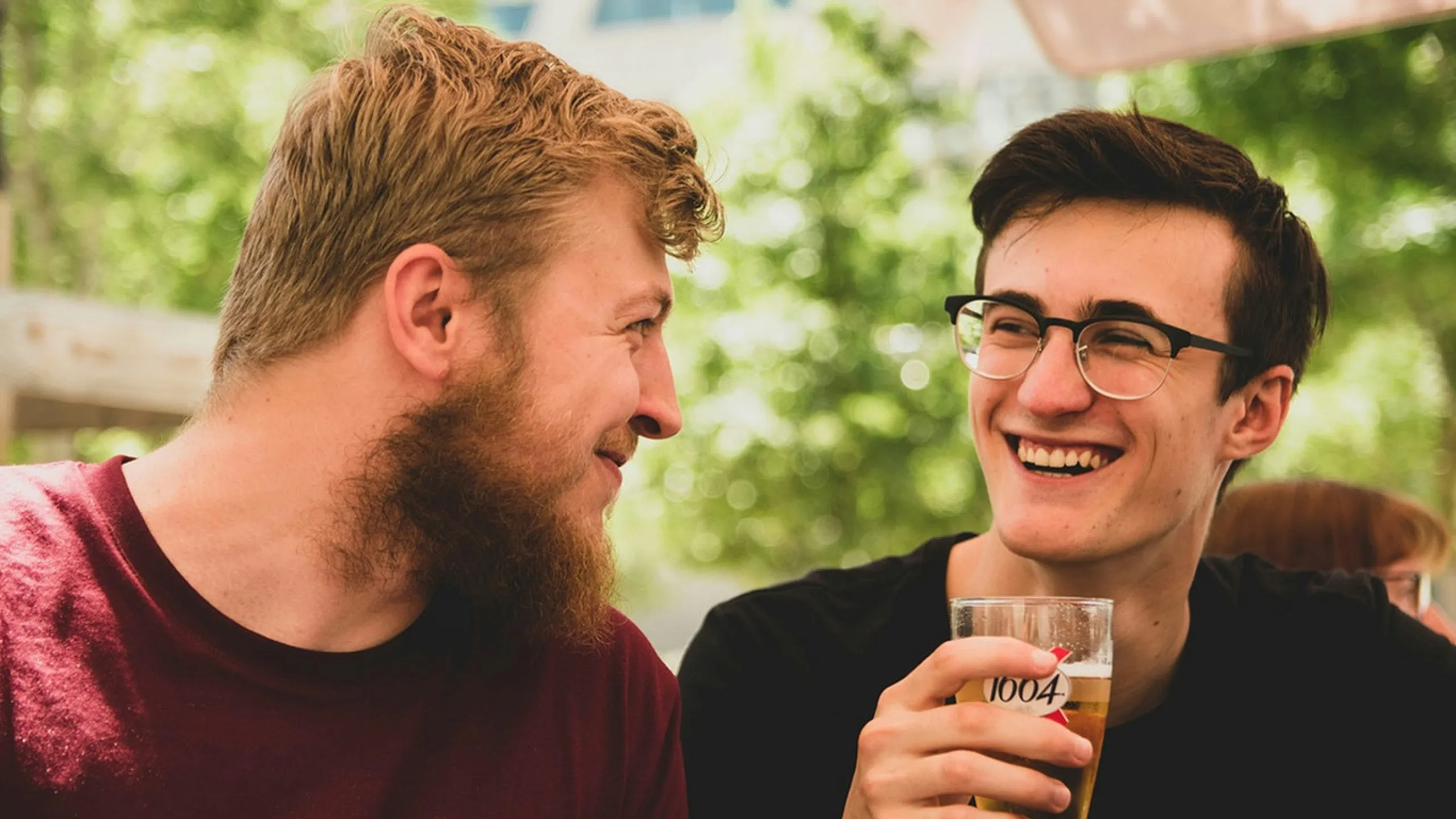 two males looking at each other with one holding a beer pint
