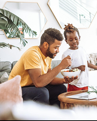 father and son sharing a bowl of food in the living room