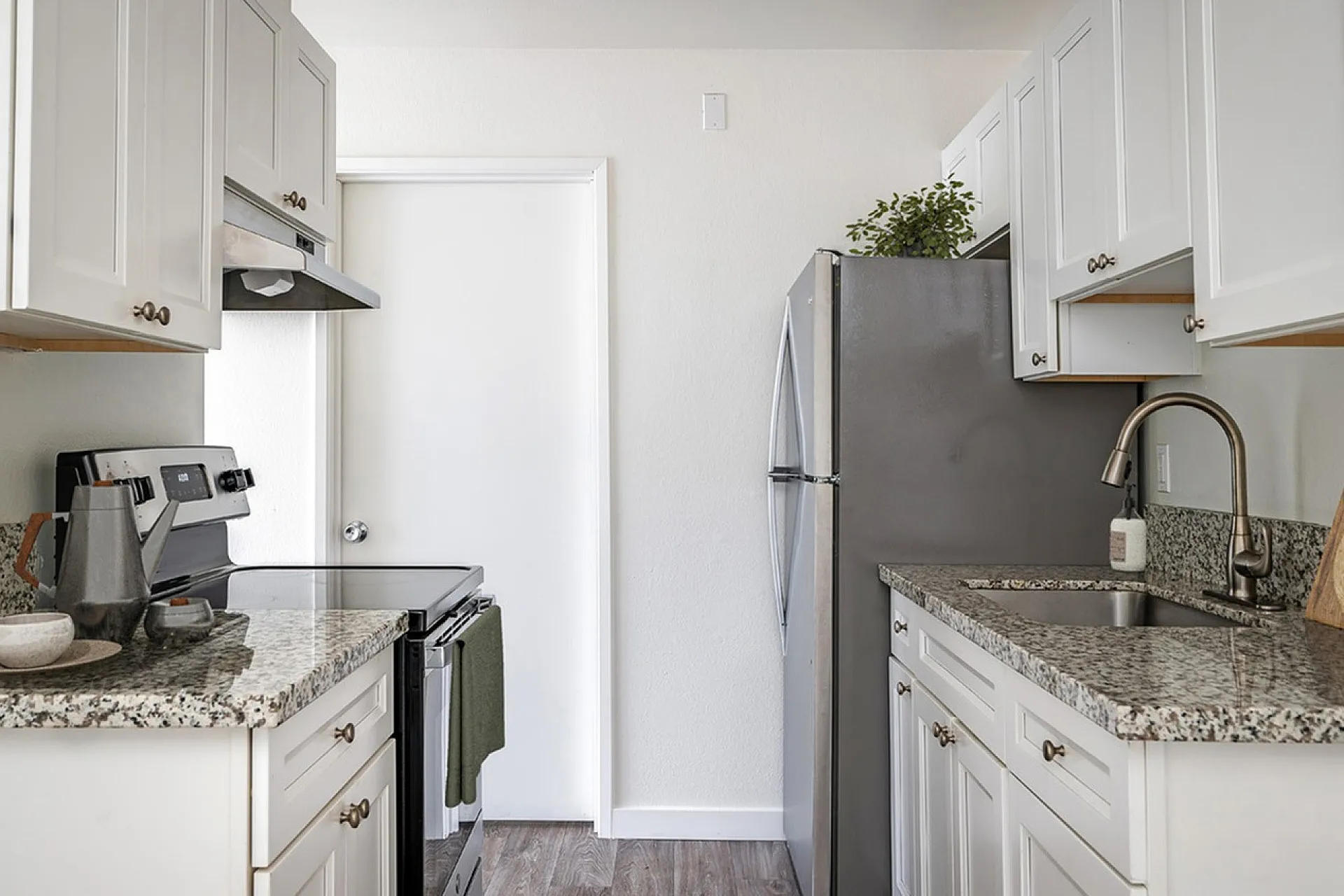 virtually staged kitchen with faux hardwood flooring and white cabinets and stainless steel appliances and decorative accessories