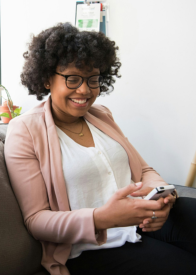 woman looking down at her phone with a smile
