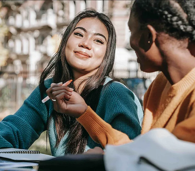 two women talking while studying outdoors