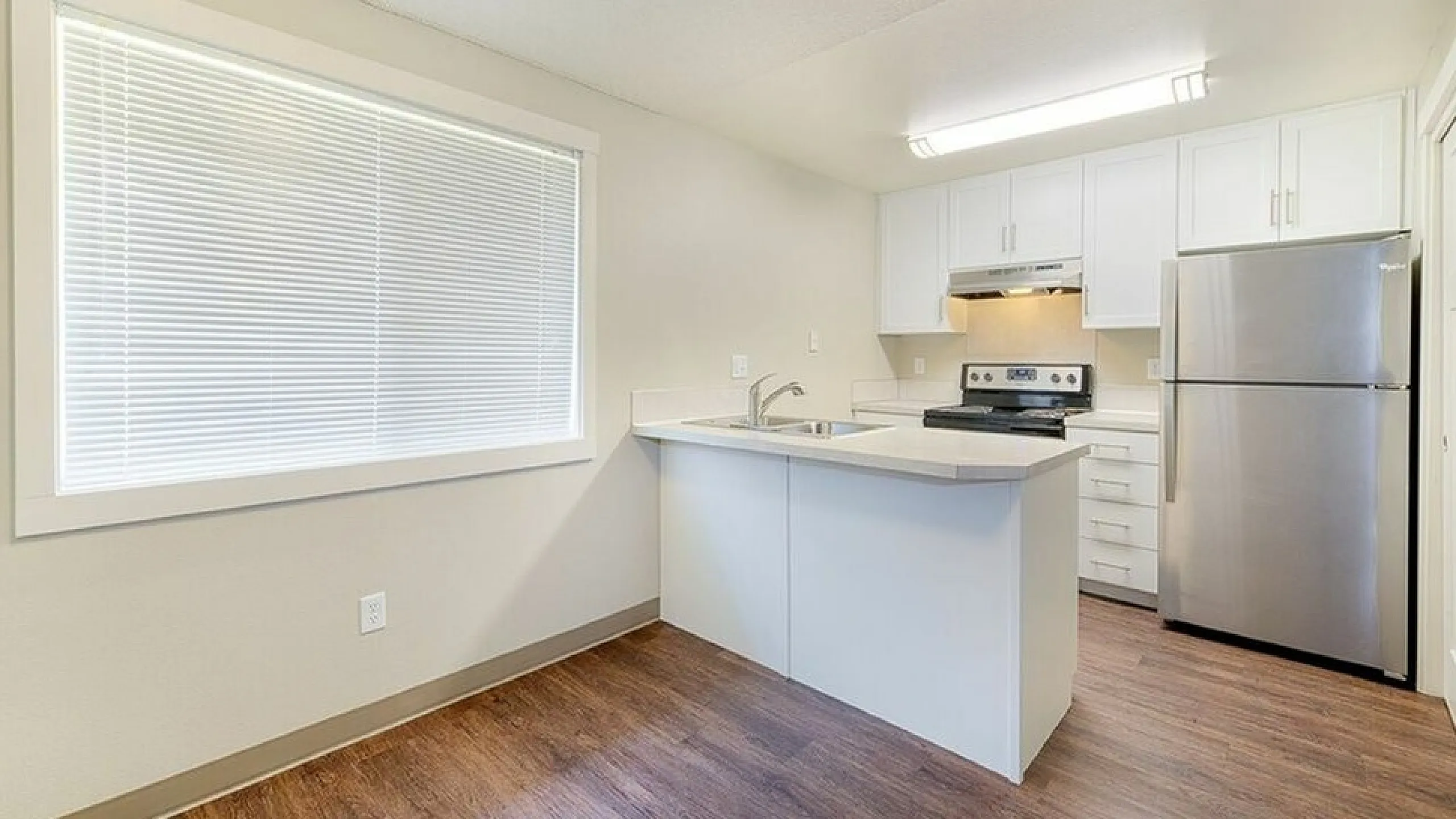 kitchen with faux hardwood flooring and stainless steel appliances at Senior Estates 1