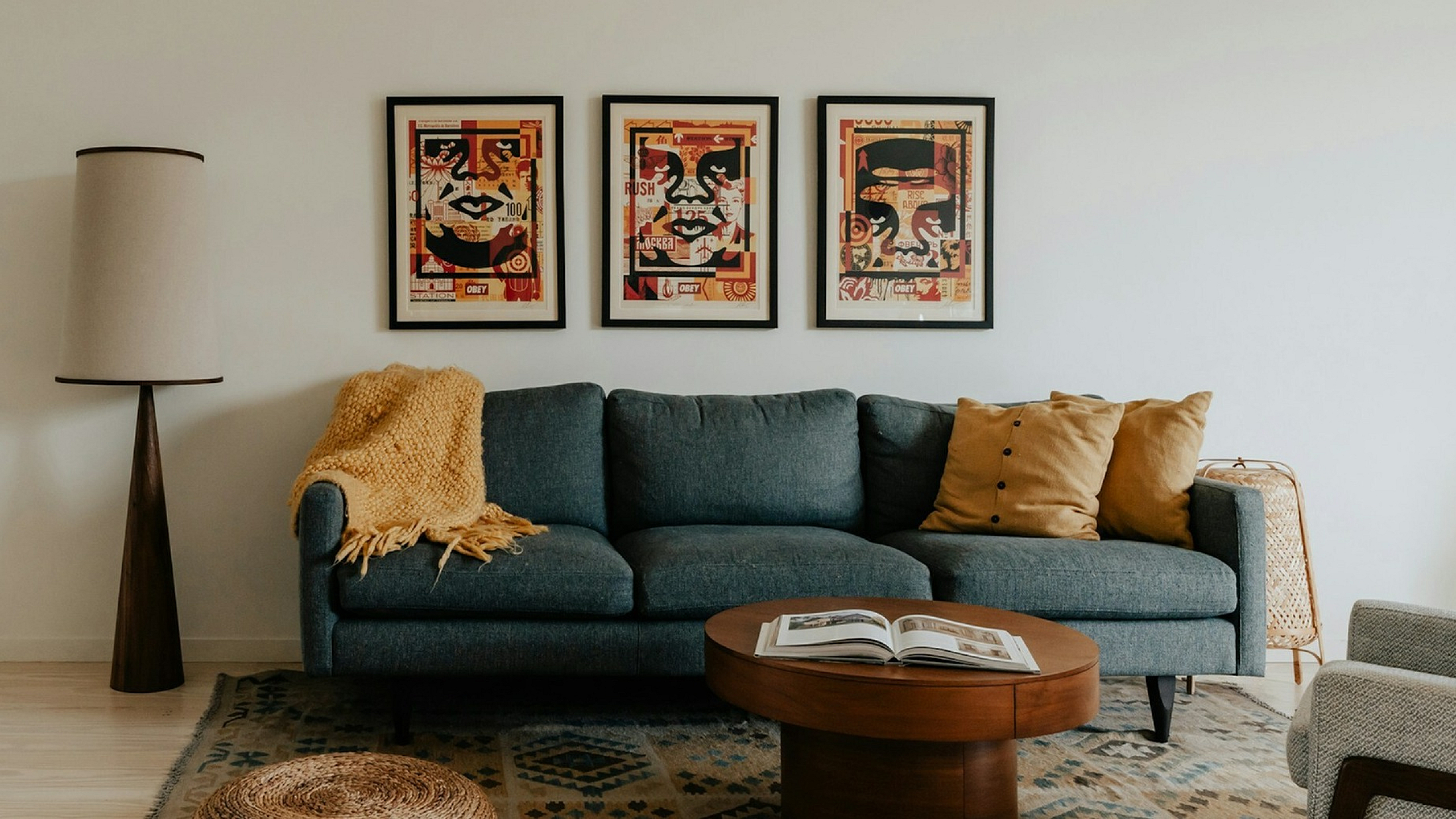 taupe 3 person sofa with art work hanging on the wall behind and a round coffee table