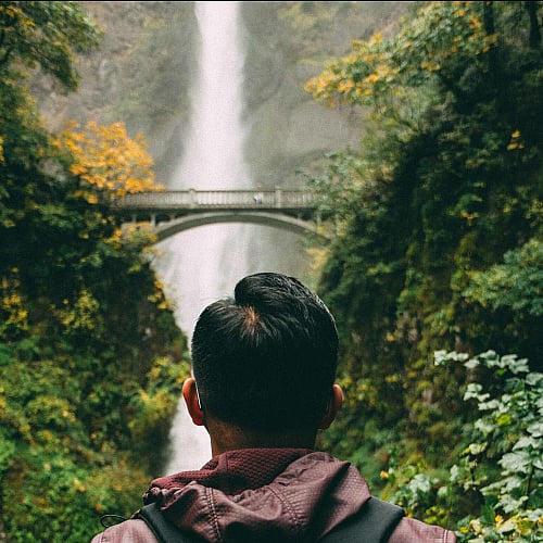 man looking at a waterfall