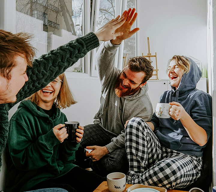 4 people drinking coffee and laughing together while sitting
