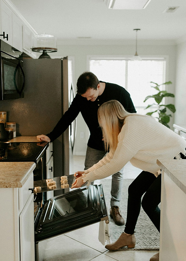 a couple putting a batch of cookies in the oven