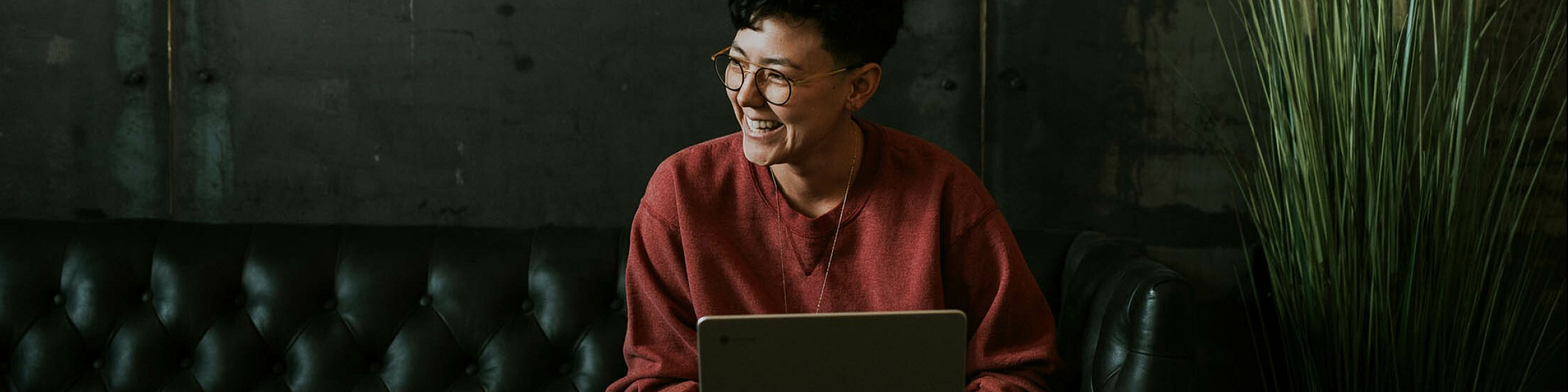 woman working on her laptop sitting on a leather sofa