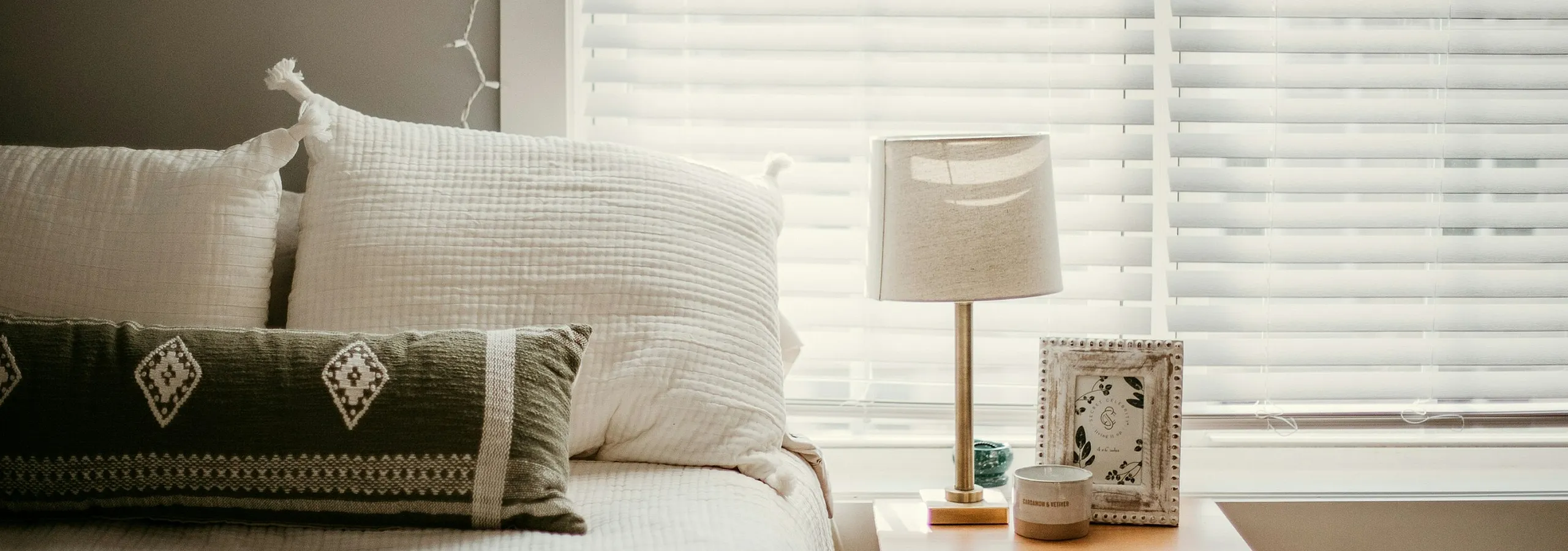 bed with green accent pillow and night stand with photo frame and lamp