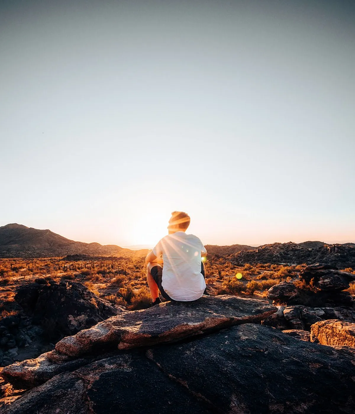van sitting on a rock looking at the sun in the desert